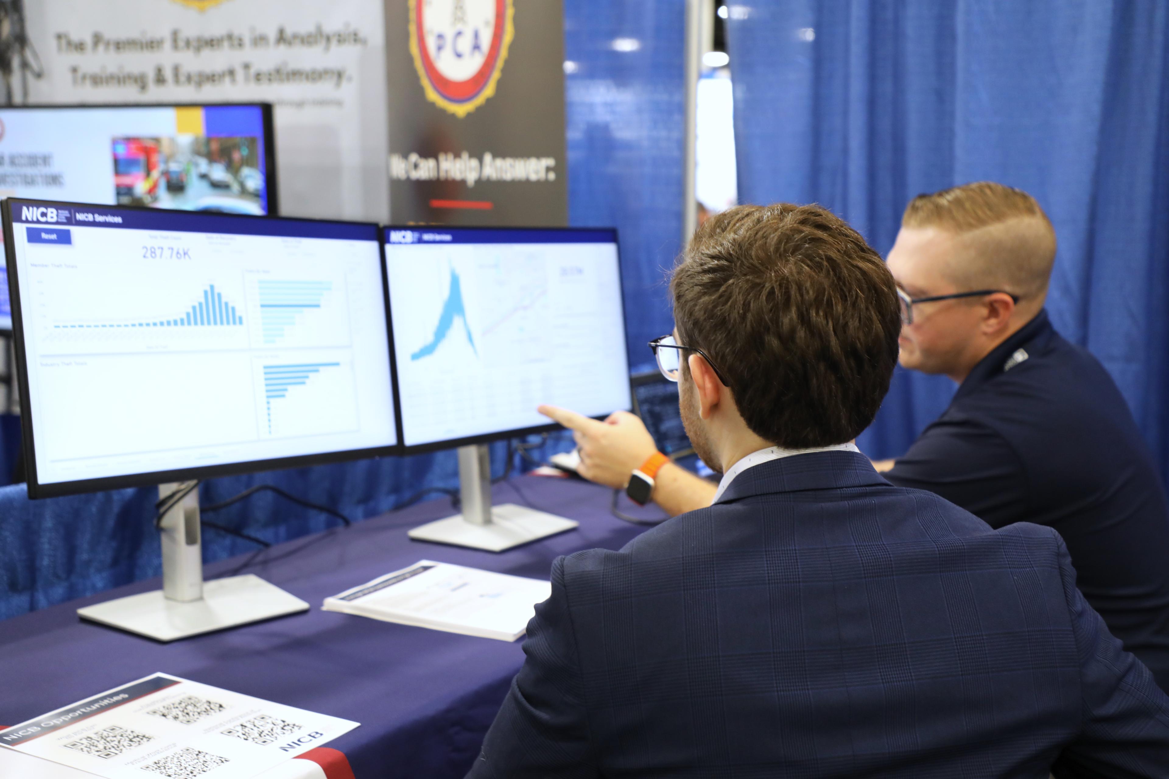 Two men looking at two monitors